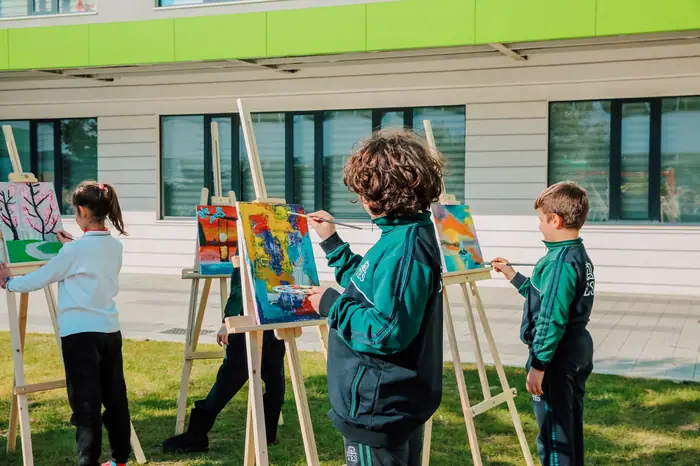 Crianças pintando em cavaletes ao ar livre com a professora