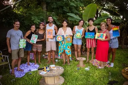 Grupo reunido ao ar livre exibindo as telas pintadas
